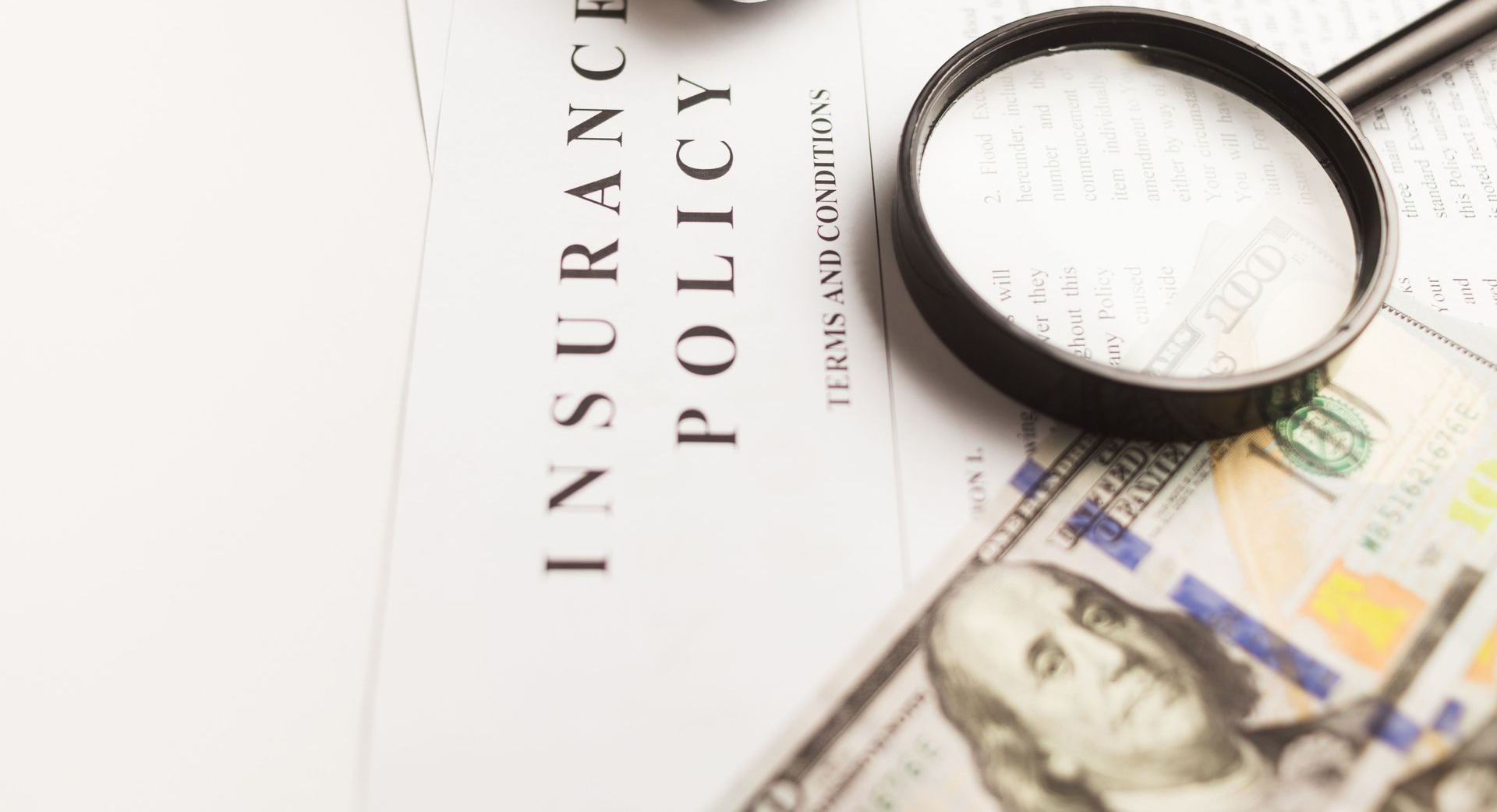 Hand writing on a check next to a red passbook and paperwork on a wooden desk