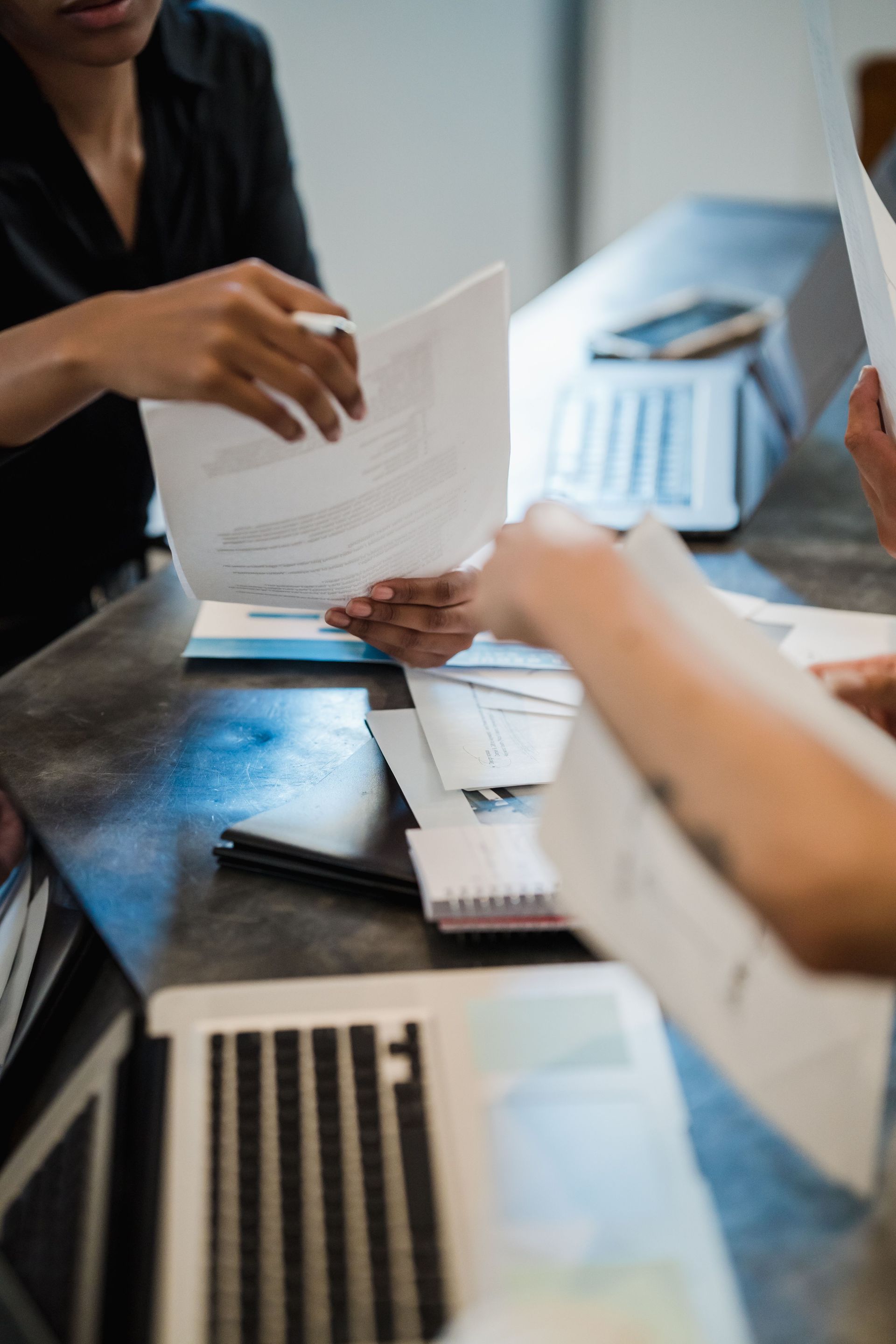 Hand writing a check on a desk beside a red notebook and papers