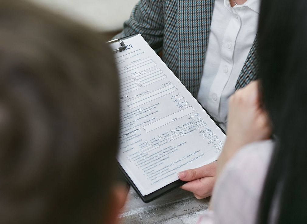 Handing over house keys beside a calculator, contract, and laptop during a real estate sale
