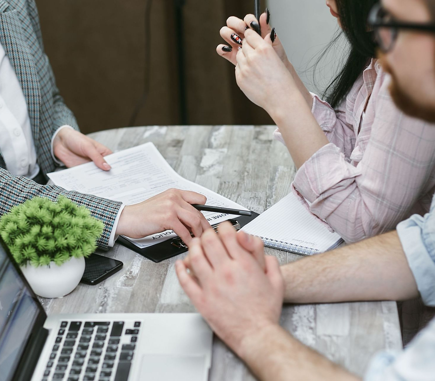 Business meeting with hands discussing documents, calculator, and laptop on a desk