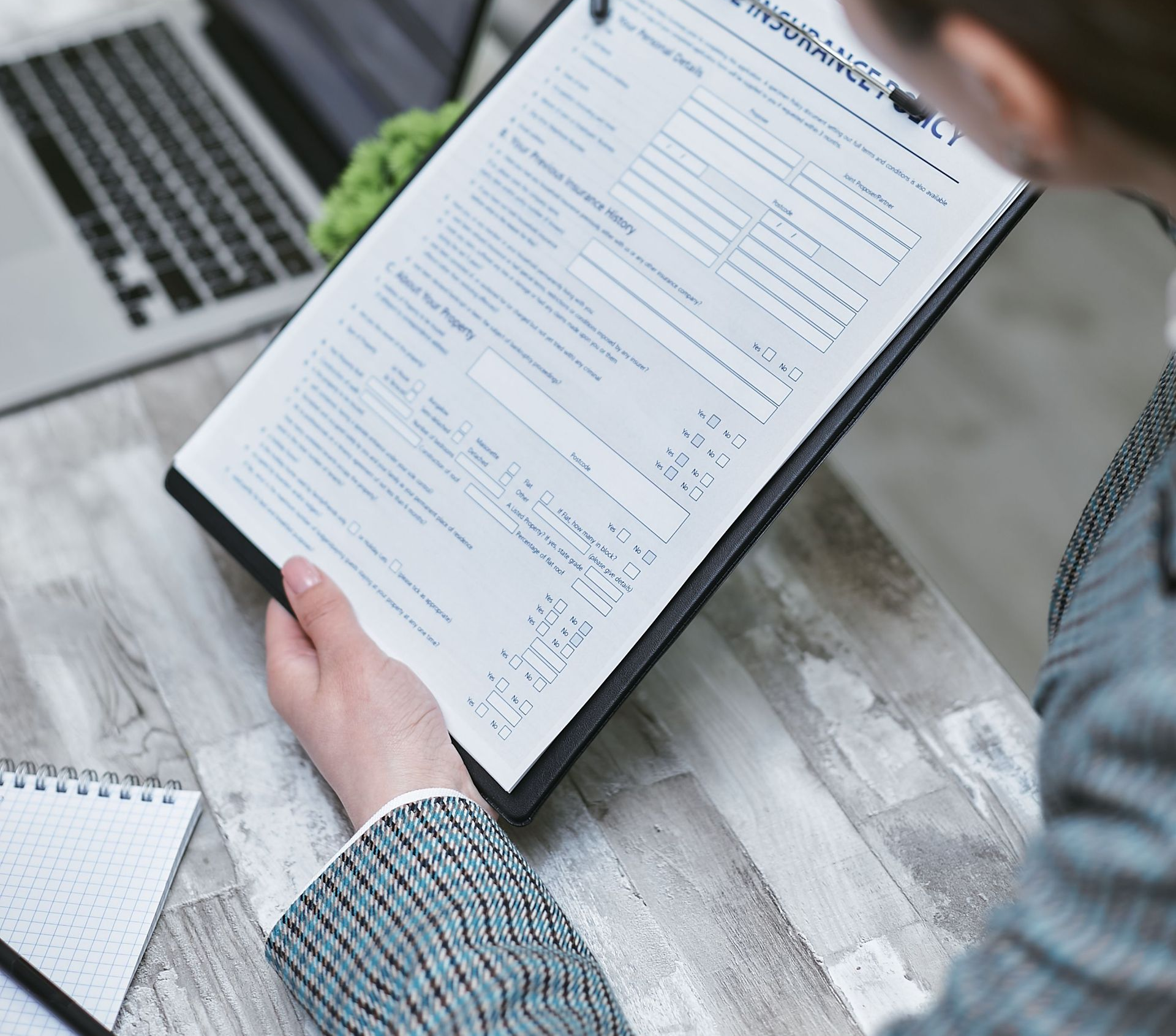 People in business attire signing documents, reviewing papers, and using a calculator at a desk.