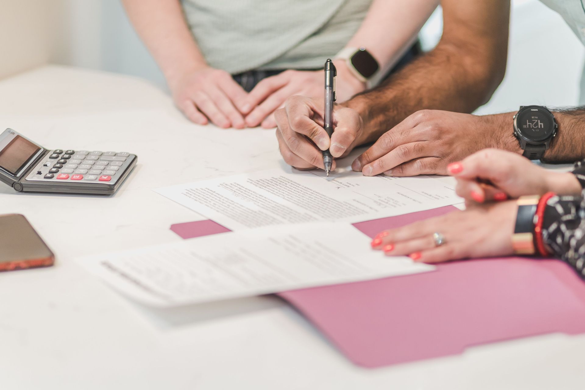 Handing over house keys beside a calculator, contract, and laptop during a real estate sale