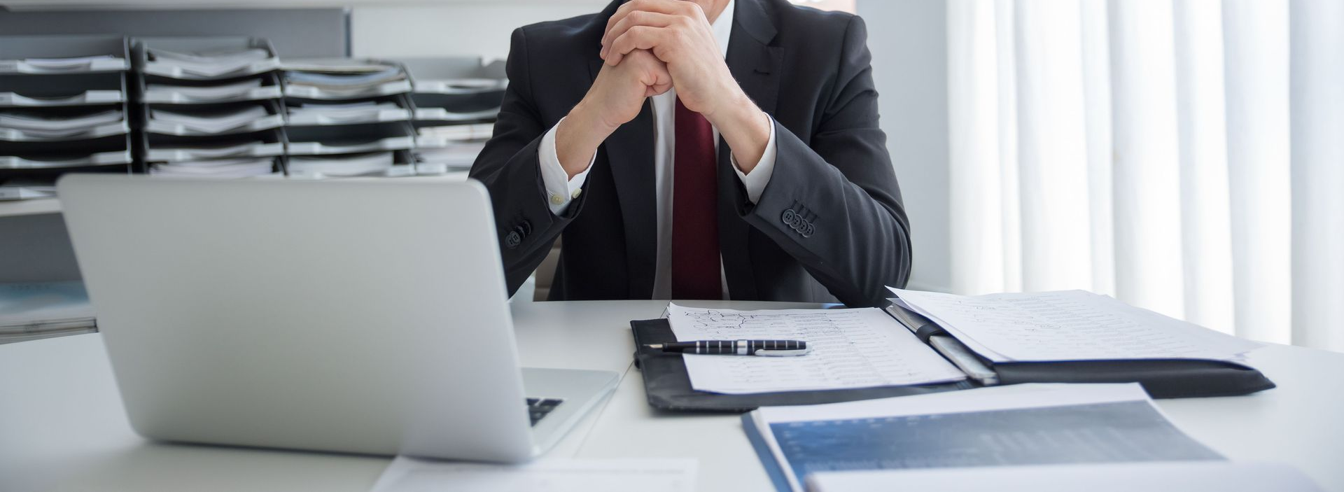 Business meeting with hands discussing documents, calculator, and laptop on a desk