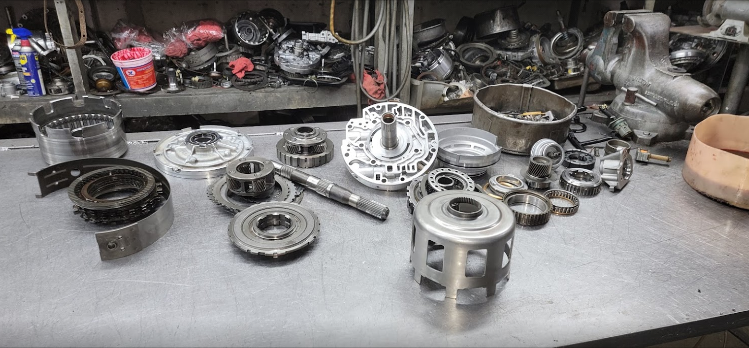 Metal engine parts and tools scattered on a workbench in a cluttered workshop