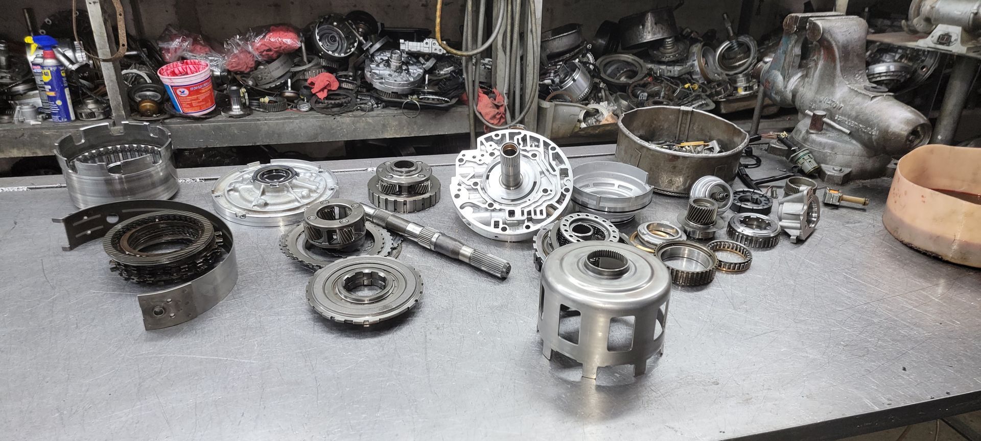 Assorted metal engine parts and bearings arranged on a workbench in a workshop