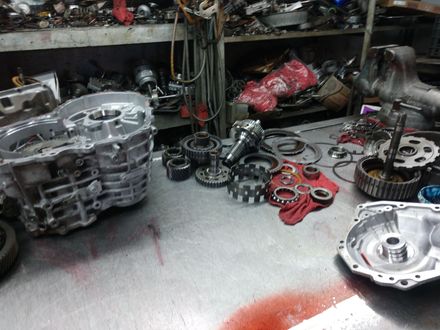 Auto parts and transmission components scattered across a workshop floor and shelves