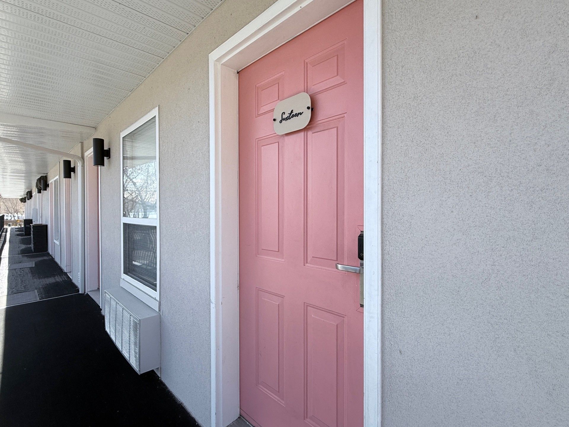 A pink motel-style door with a small sign that reads 