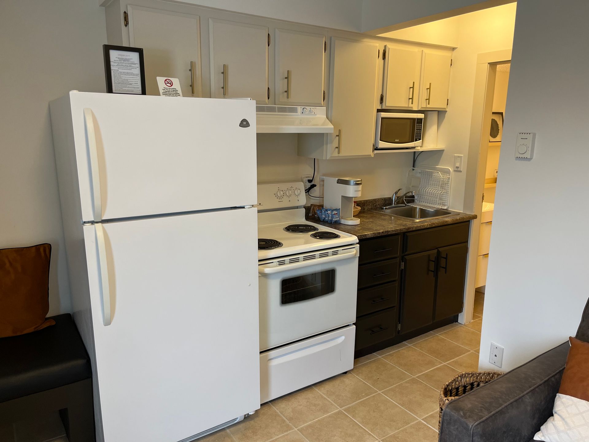 Small kitchen with a white refrigerator, white gas stove, brown cabinets, and a microwave above the sink area.