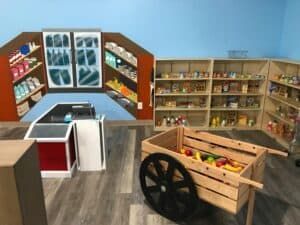 A toy grocery store with a cart filled with fruit and vegetables.