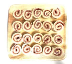 A wooden tray filled with swirls of food on a white background.