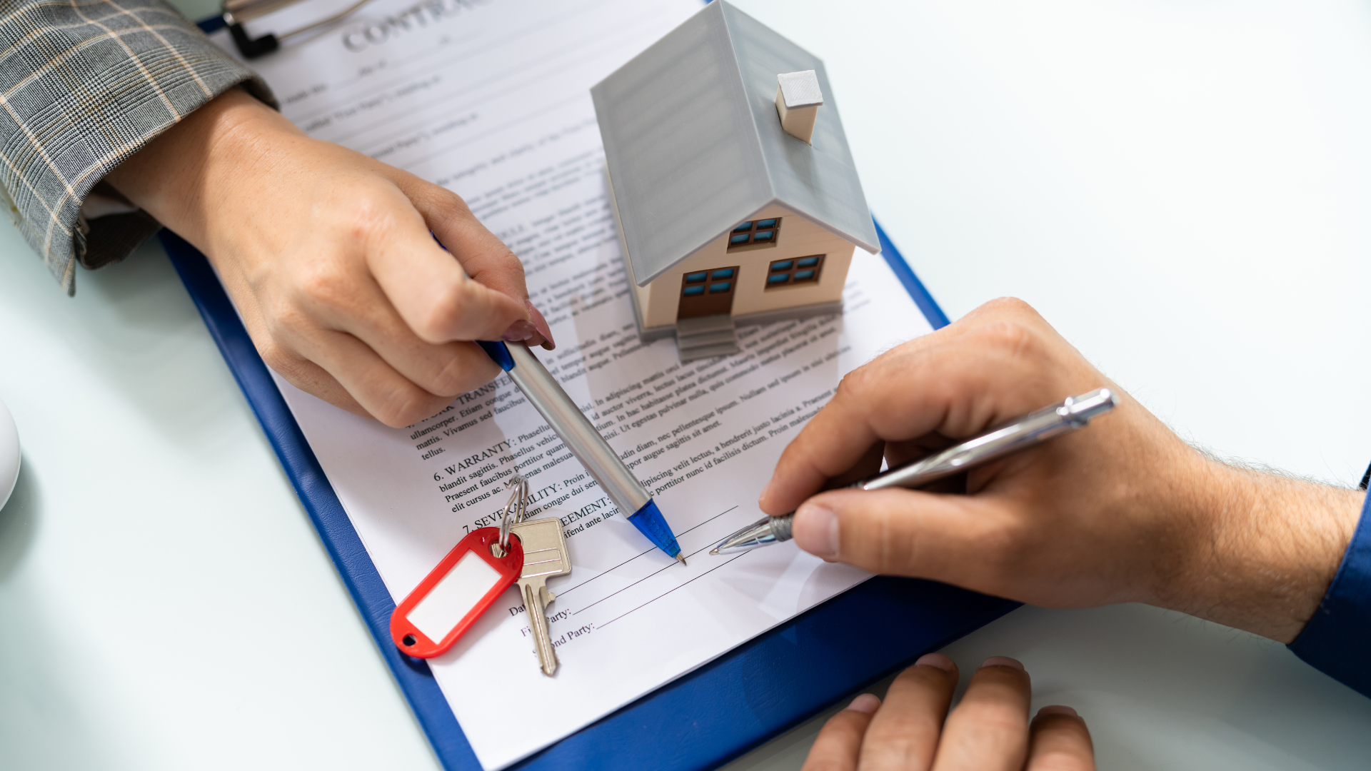 A person is signing a contract with a model house and keys.