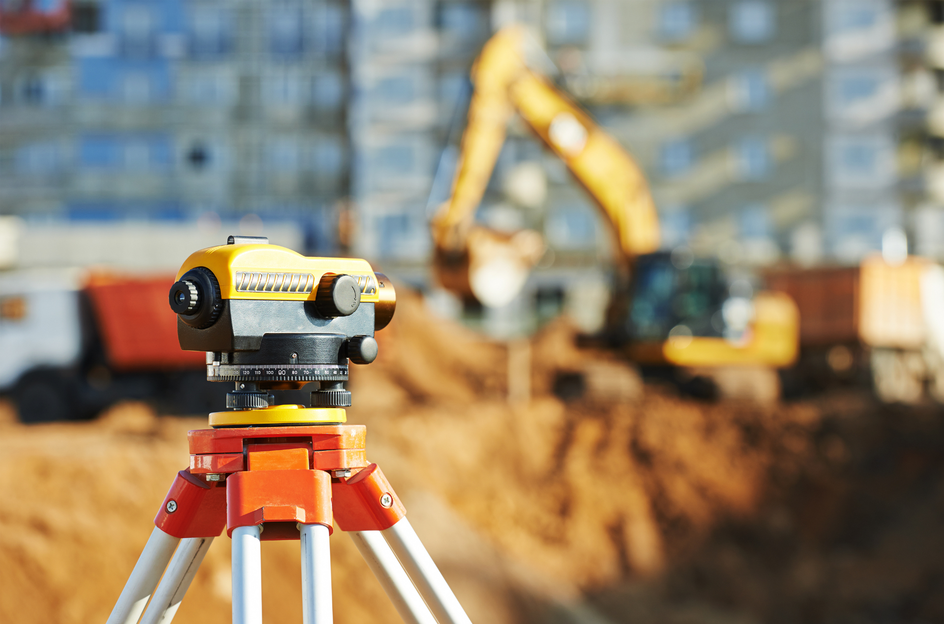 A level is sitting on a tripod at a construction site.