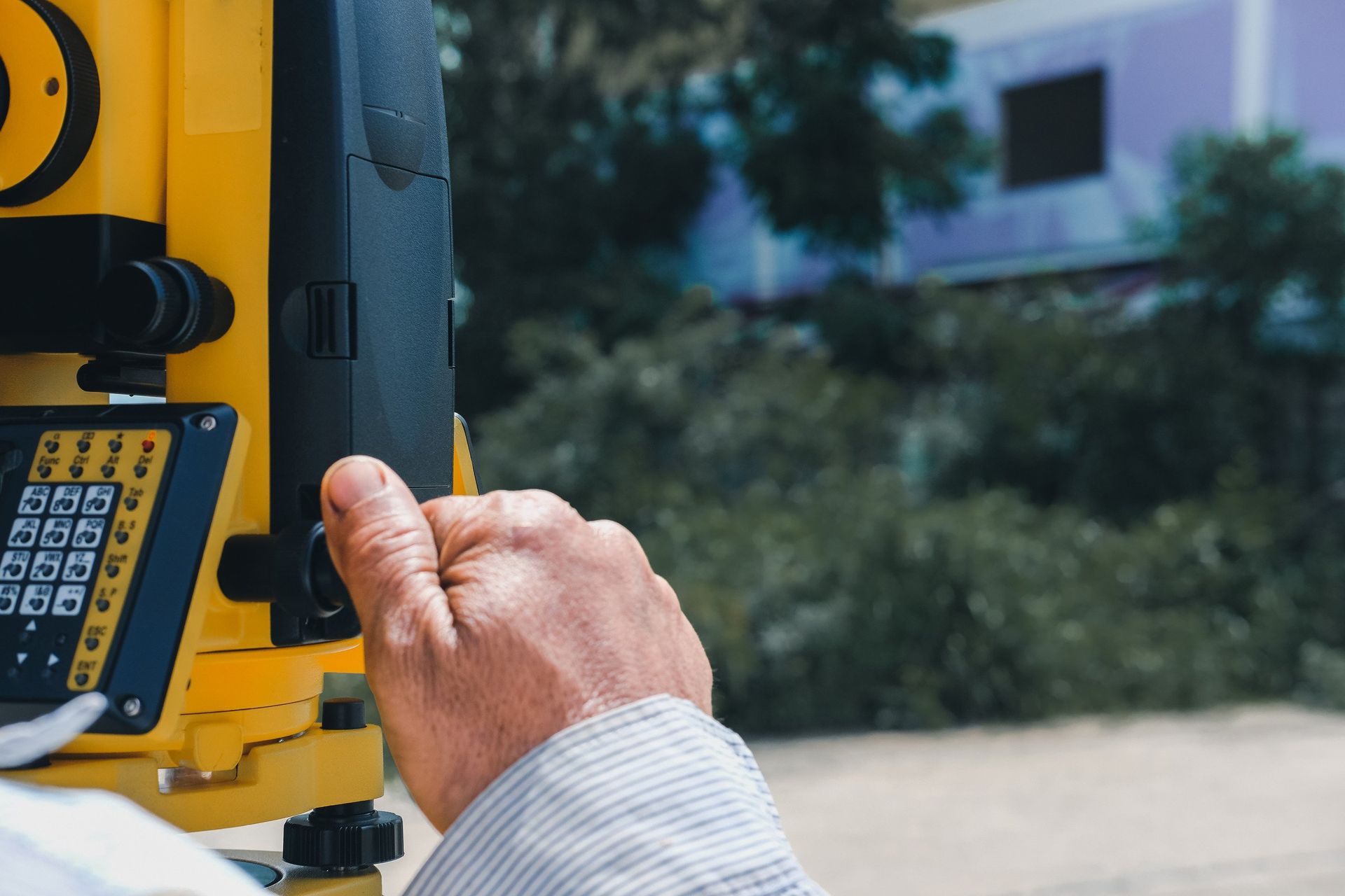 A man is using a topographic device to measure a building.