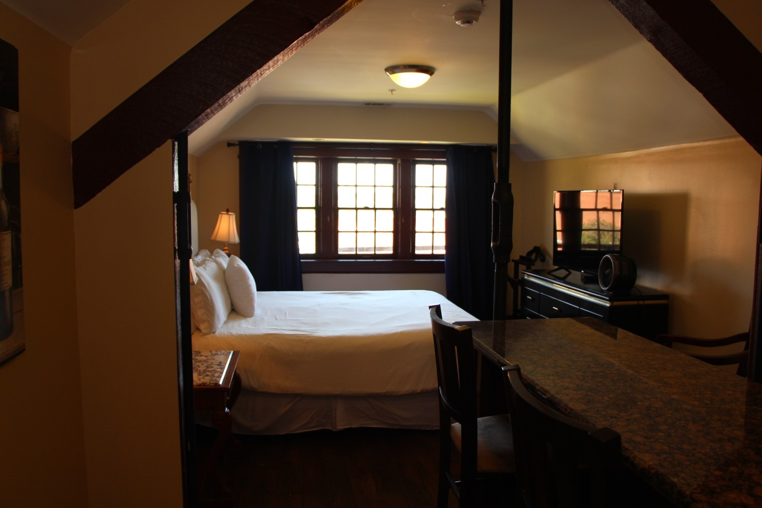 Bedroom with bed, dresser, window, and small bar in front.