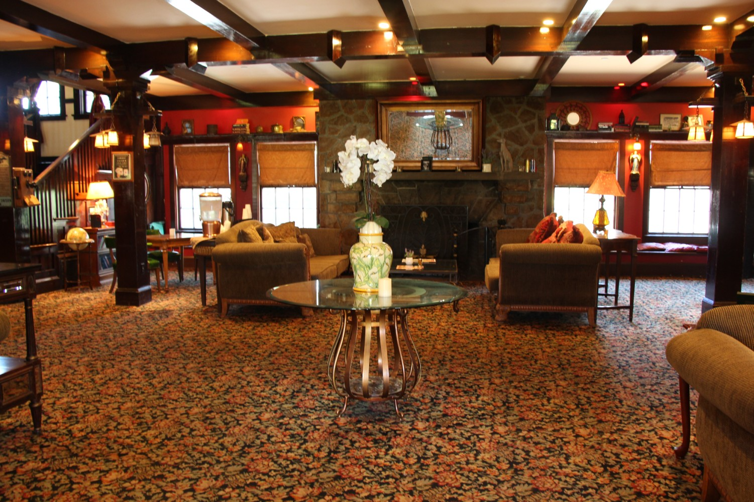 Cozy interior with dark wood beams, ornate fireplace, and seating areas with lamps.