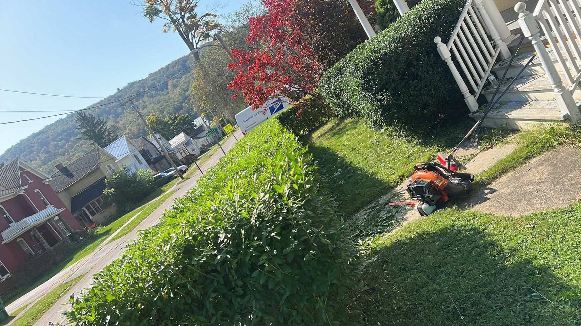 A hedge trimmer is sitting on the sidewalk next to a house.