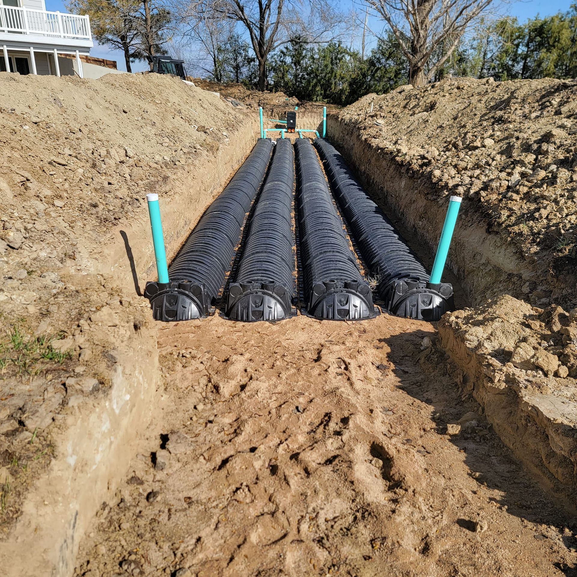 a row of black pipes are sitting in the dirt in a trench .