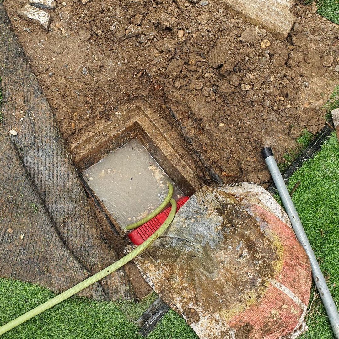 a broom is sitting in the dirt next to a hose .