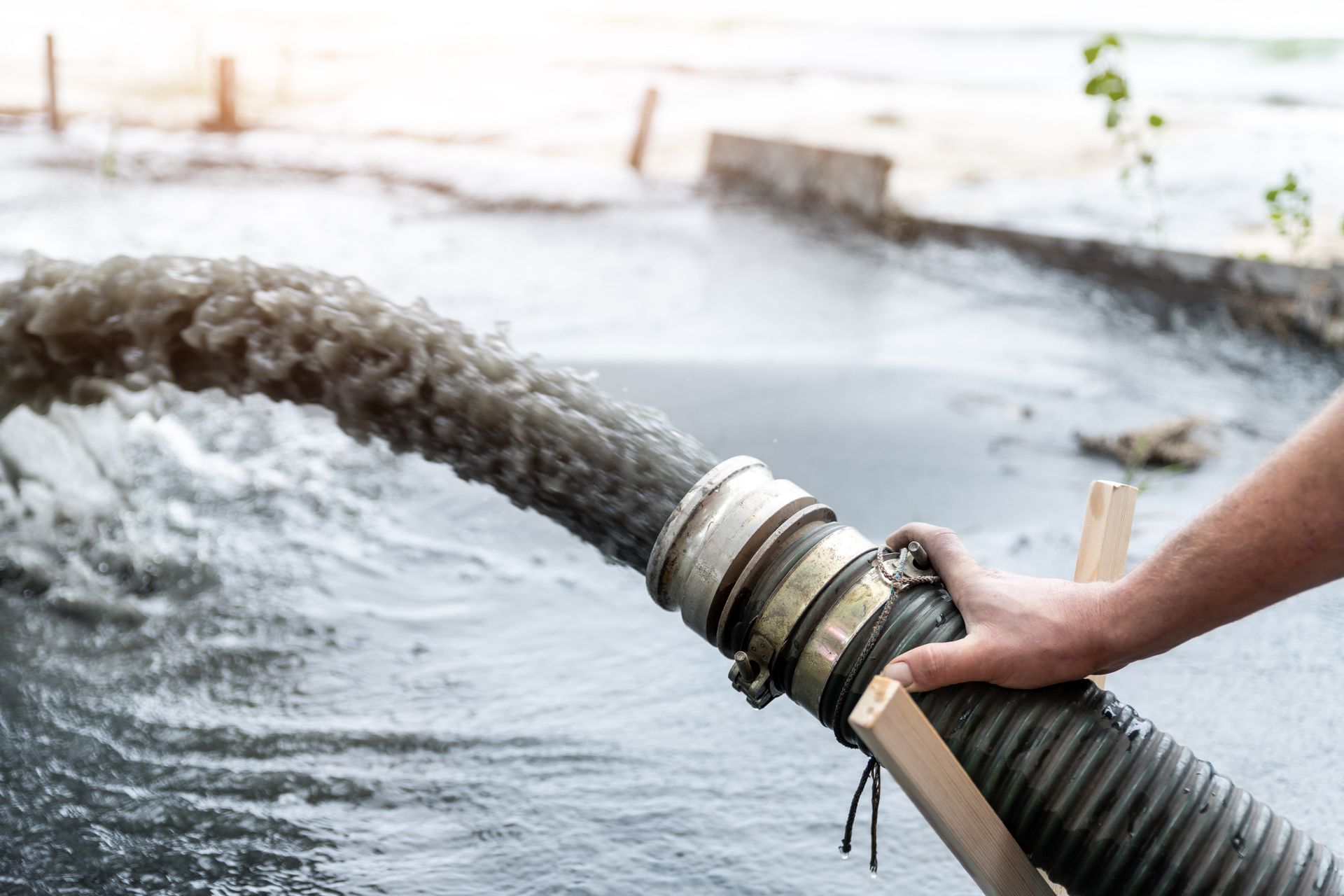 a person is pumping water from a hose into a body of water .