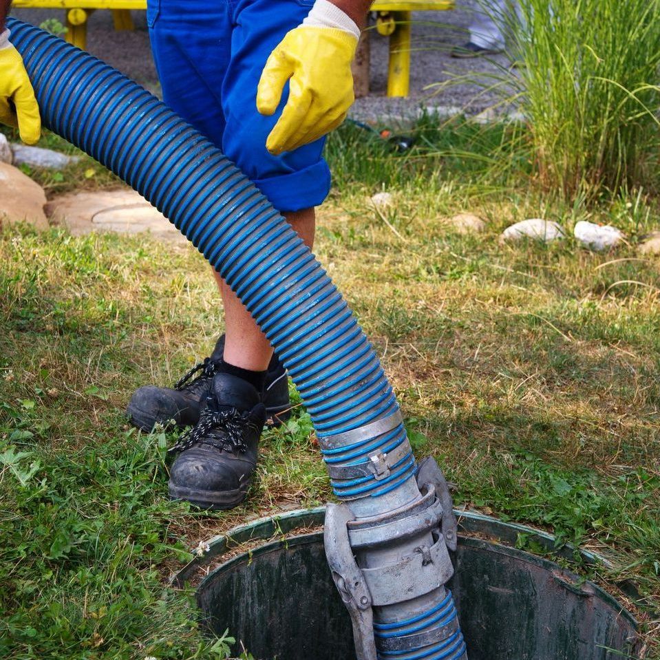 a man is pumping a hose into a septic tank .