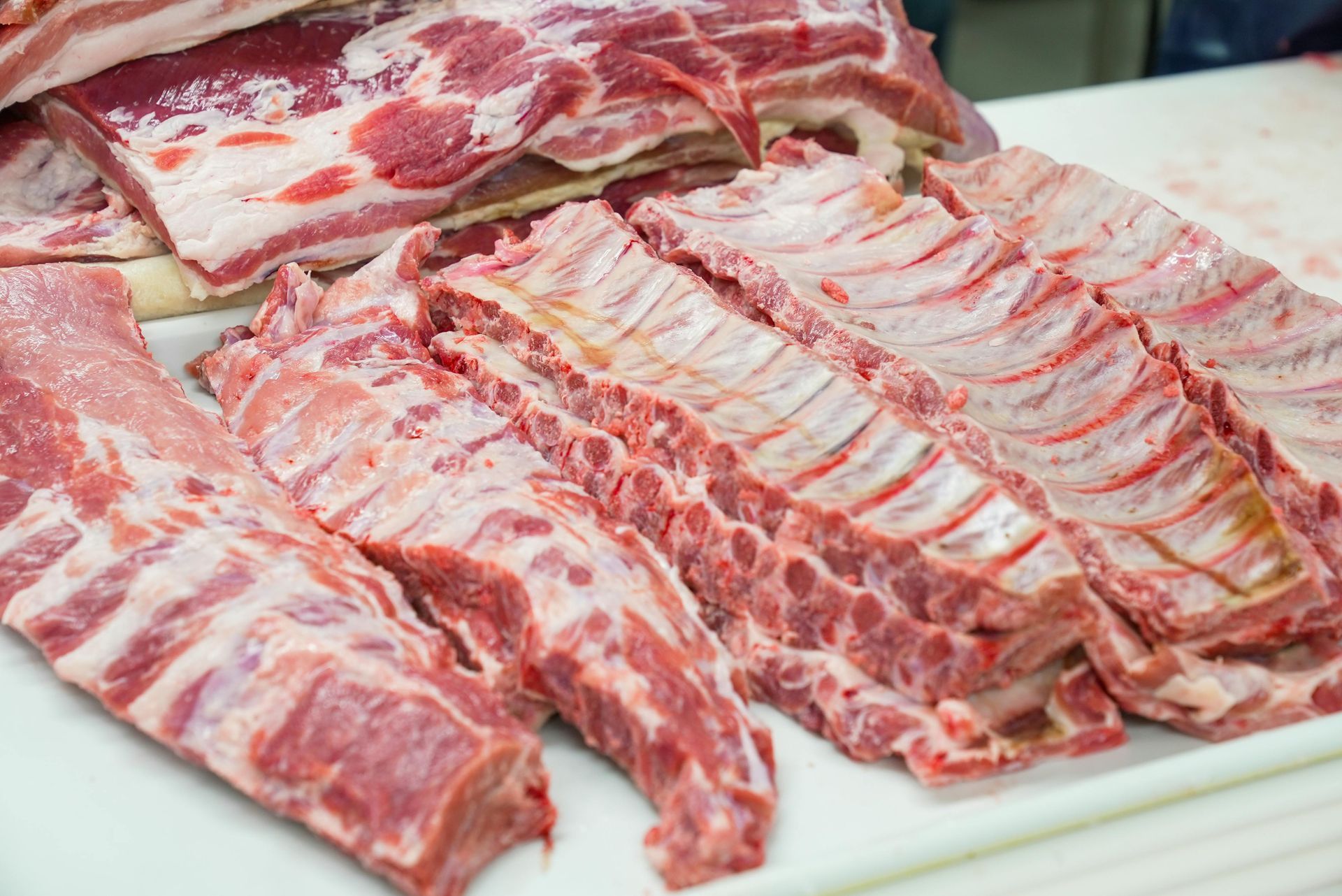 A pile of raw meat is sitting on top of a white cutting board.