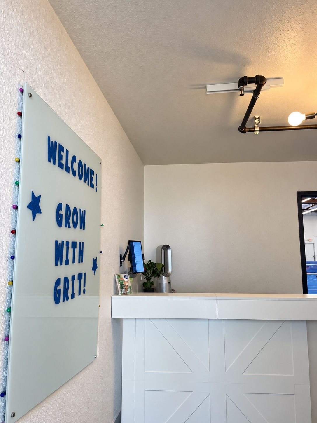 White front desk beside the Welcome, Grow with GRIT sign.
