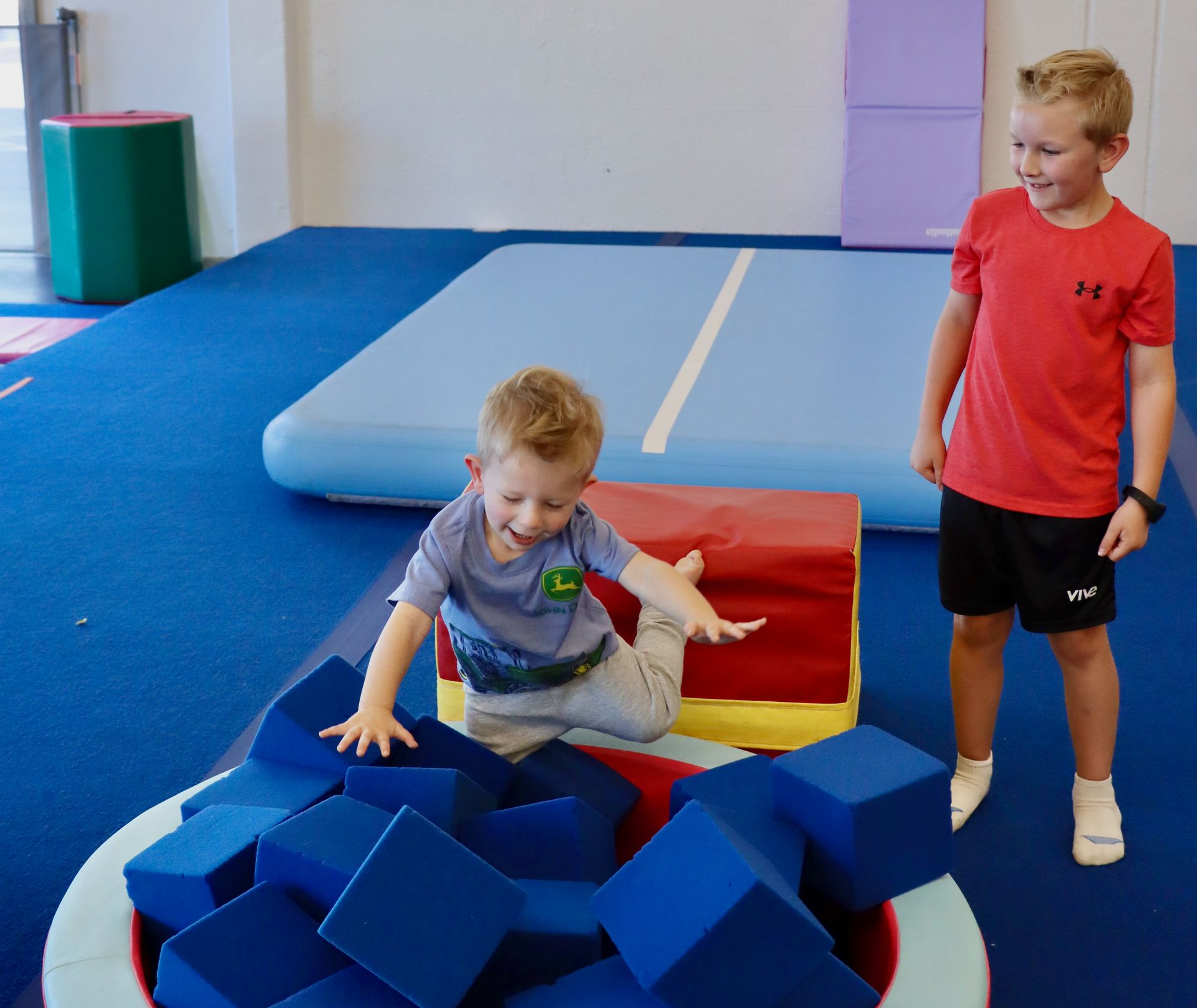 Smiling child in a blue top holding a colorful rainbow ball indoors