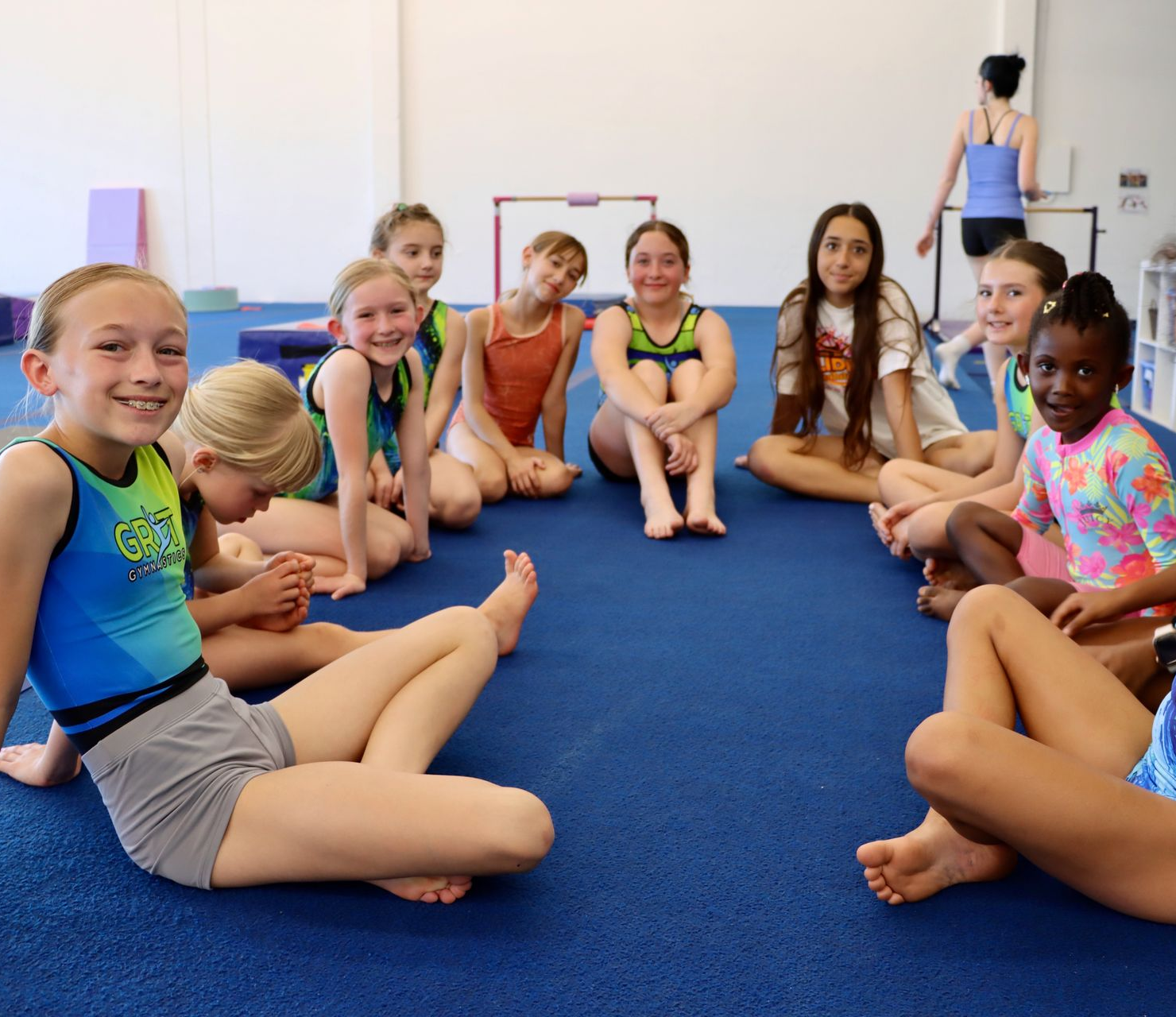 Smiling child in a blue top holding a colorful rainbow ball indoors
