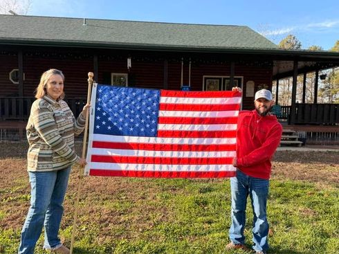 Two people holding a large American flag in front of a building