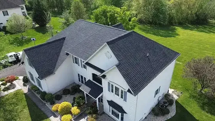 Aerial view of a white two-story house with a dark roof and landscaped yard.