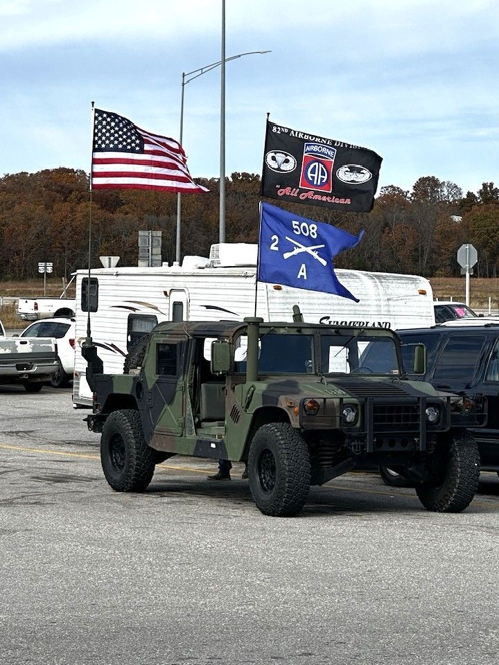 Military vehicle with American and POW/MIA flags in a parking lot
