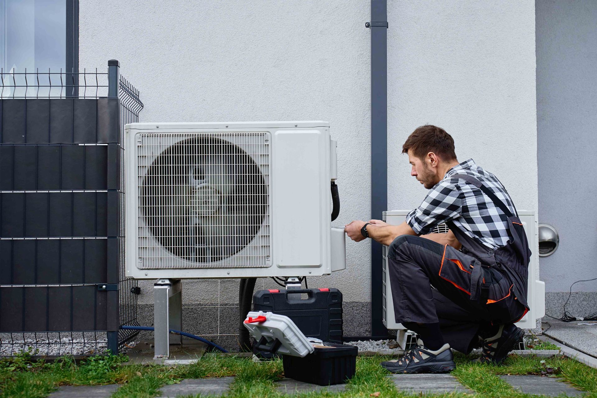 Residential HVAC contractor servicing an outdoor air conditioning unit at home. Residential HVAC contractor servicing an outdoor air conditioning unit at home.