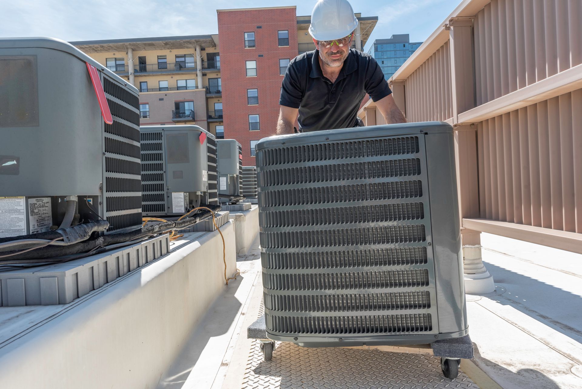 HVAC technician inspecting or servicing rooftop air conditioning condenser units on a building. HVAC technician inspecting or servicing rooftop air conditioning condenser units on a building.