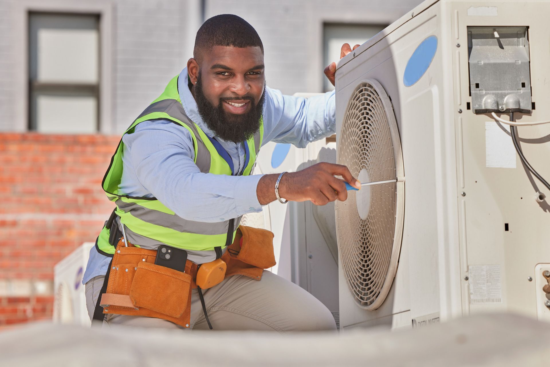 Portrait of a smiling technician from an HVAC company, performing AC repair on a rooftop. Portrait of a smiling technician from an HVAC company, performing AC repair on a rooftop.