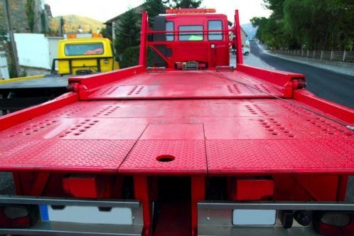 A red tow truck is parked on the side of the road