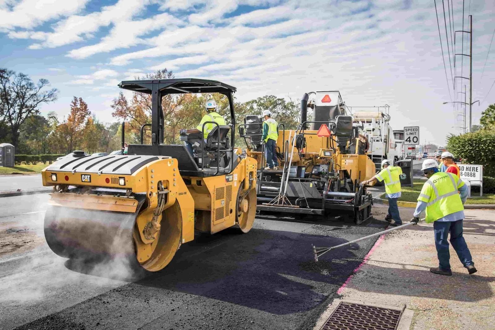 Road crew paving a street with heavy machinery and workers in reflective vests