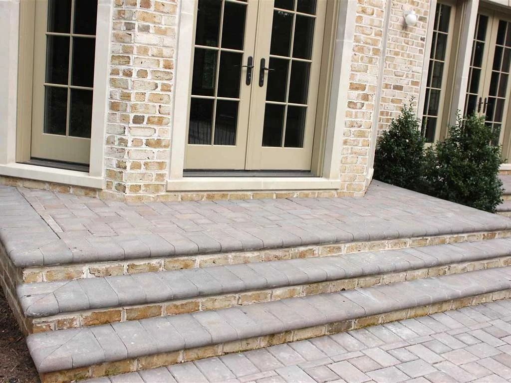 Stone steps leading to beige double doors on a brick house exterior