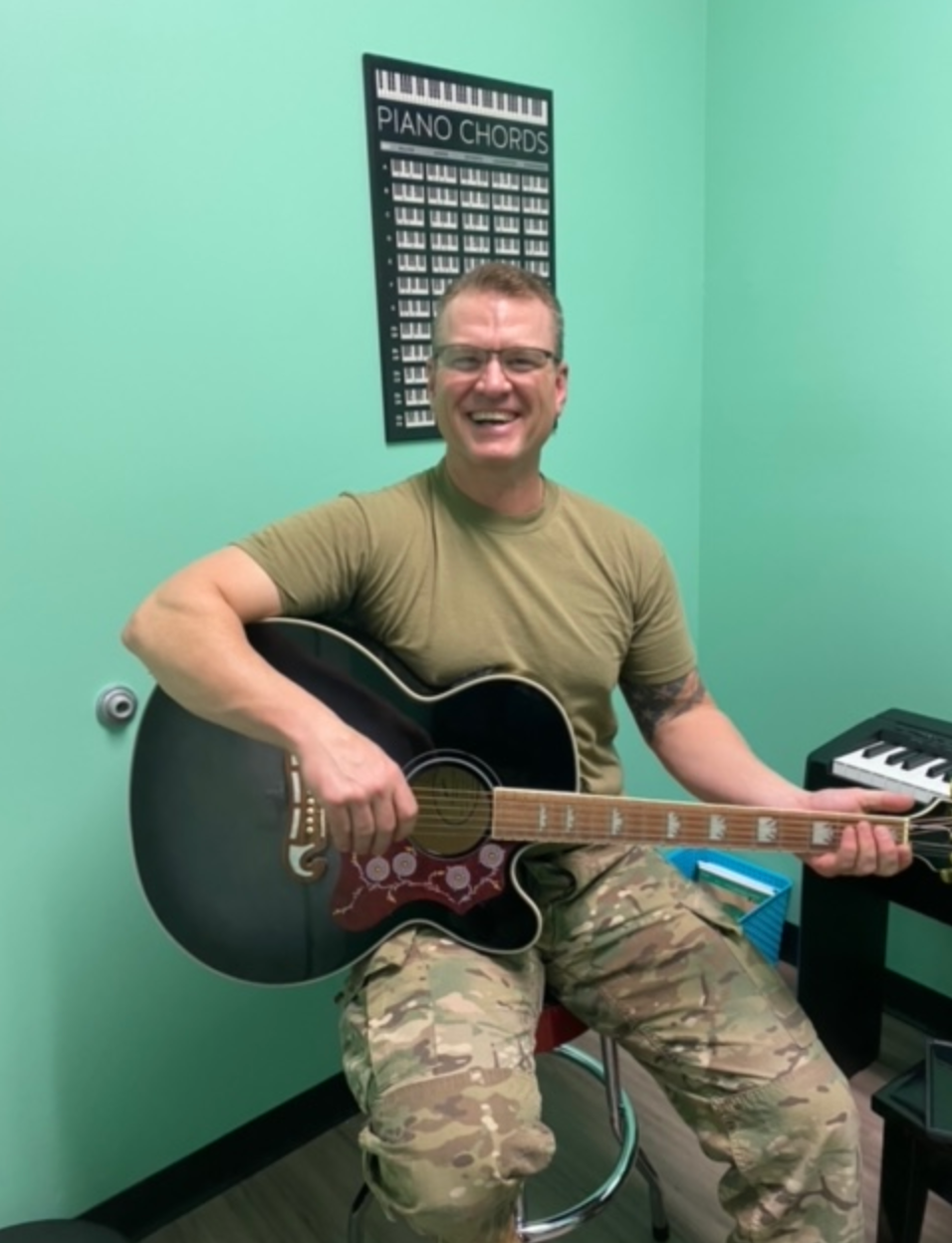 A man in a military uniform is playing an acoustic guitar