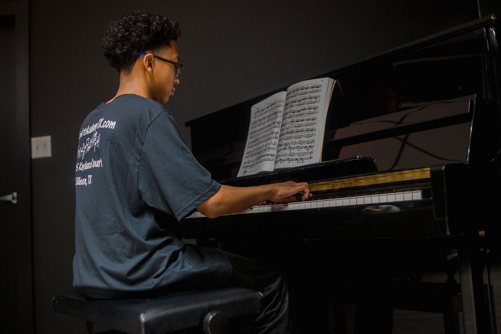 A young man is playing a piano in a dark room.