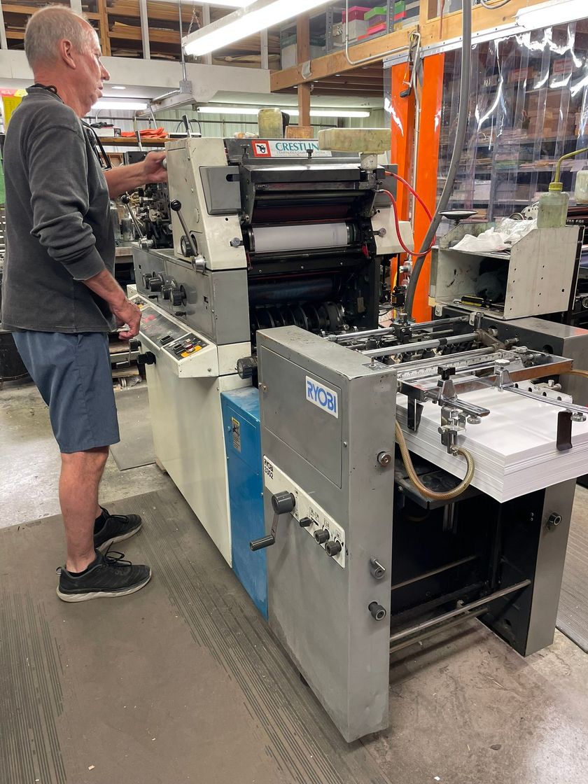A man is standing in front of a machine in a factory.