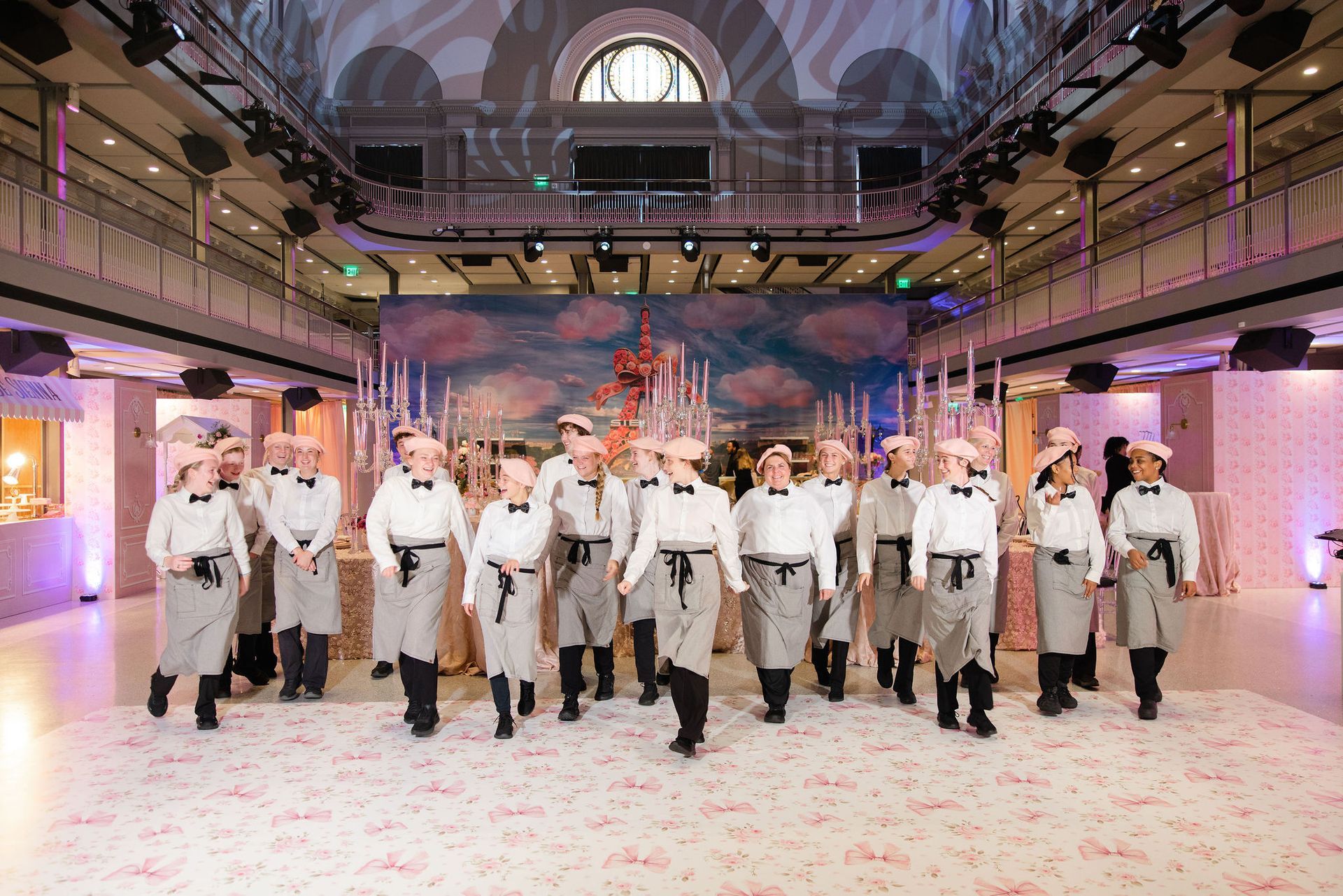 Uniformed dancers perform in a grand ballroom with a decorated stage backdrop.
