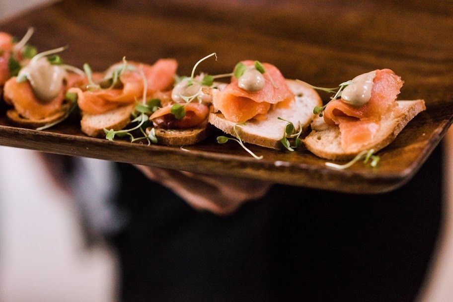 Tray of smoked salmon canapés garnished with greens on a rustic serving board