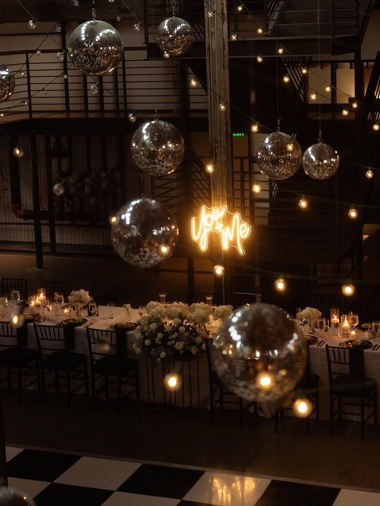 Elegant banquet hall with mirrored disco balls, warm string lights, and a long decorated dinner table