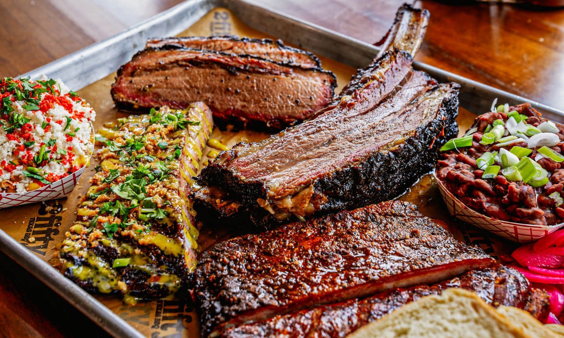 Platter of grilled meats and sausages with herbs and chopped vegetables on a wooden table