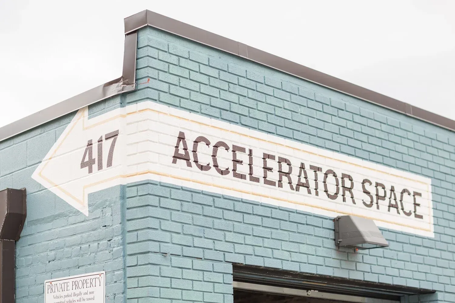 White arrow sign on a teal building reads “ACCELERATOR SPACE” with number 417.