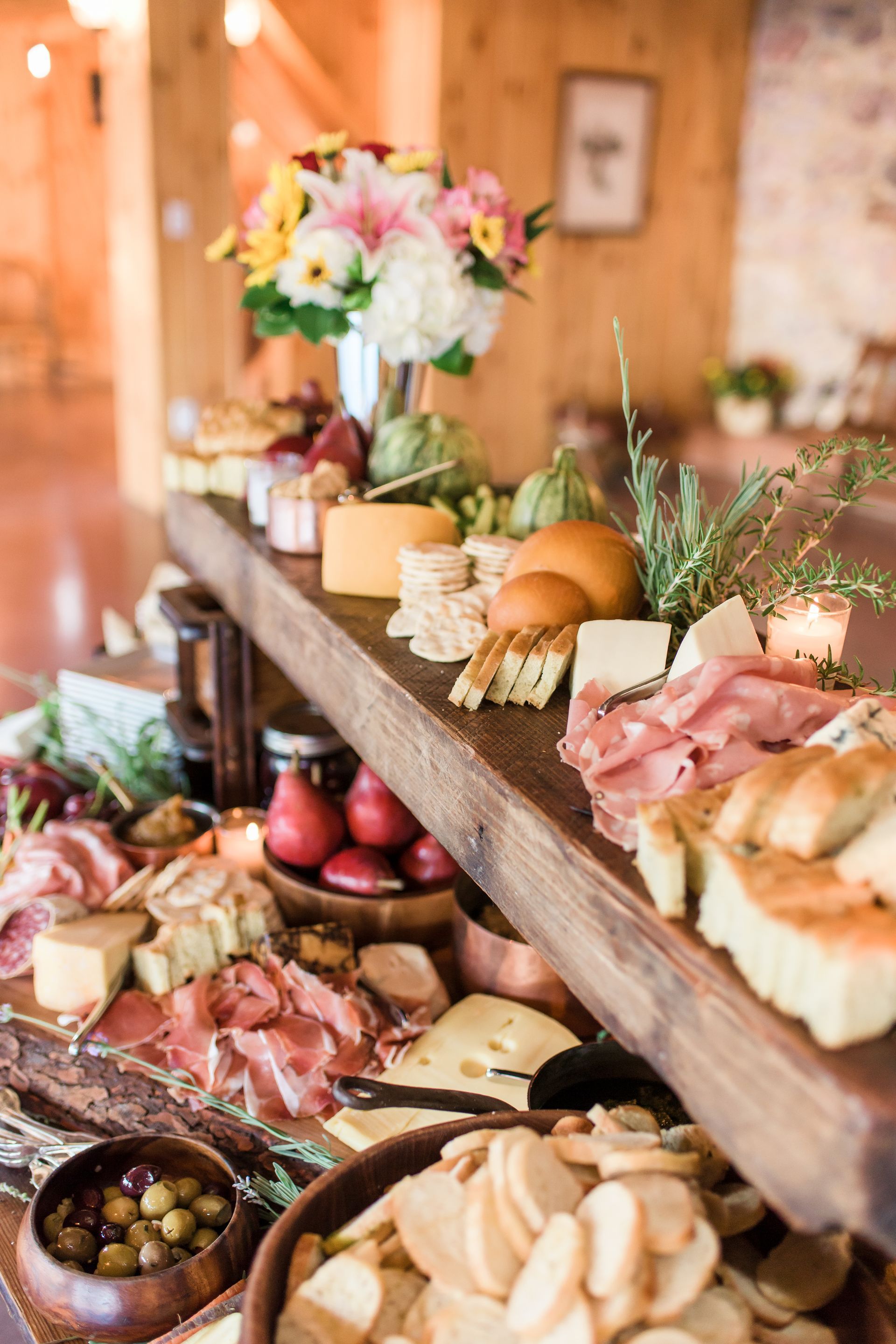 Elegant buffet table with pastries, meats, fruit, and flowers in a warm indoor setting