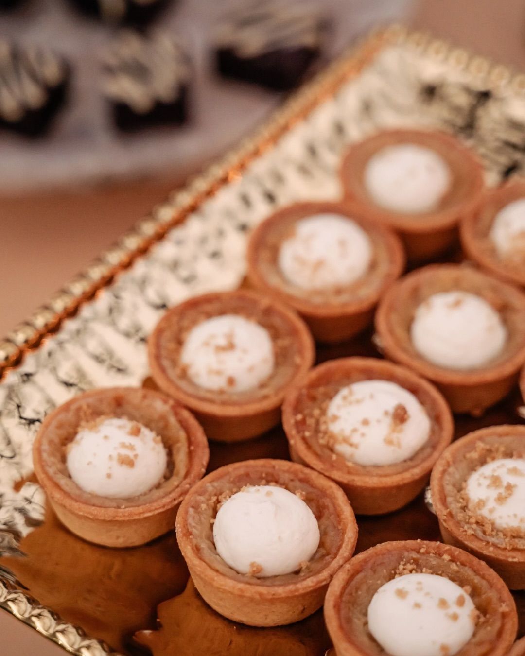 Tray of small tart desserts topped with white cream and cinnamon