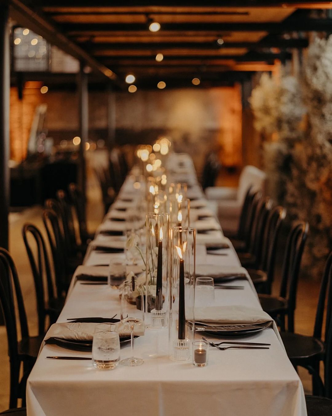 Long dining table set for a formal event in a warmly lit restaurant room