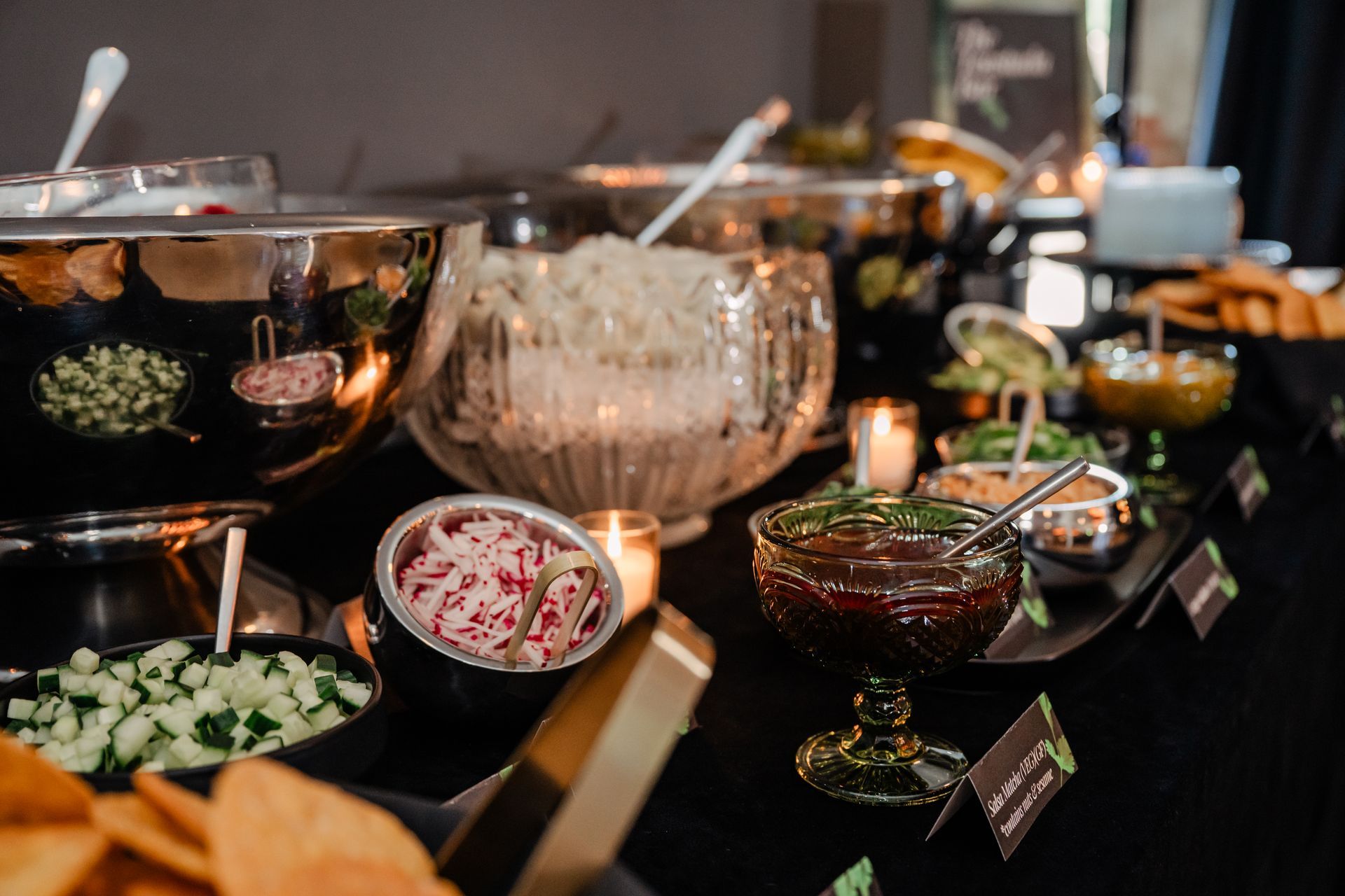 Tray of assorted bite-sized appetizers on wooden boards, served by a person in a white shirt at an outdoor event