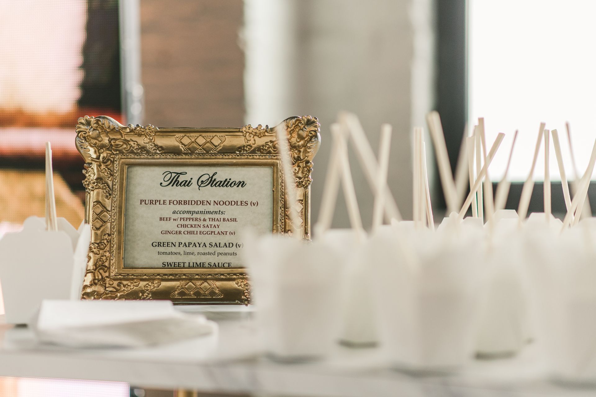 Framed gold sign beside white paper favor bags on a dessert table